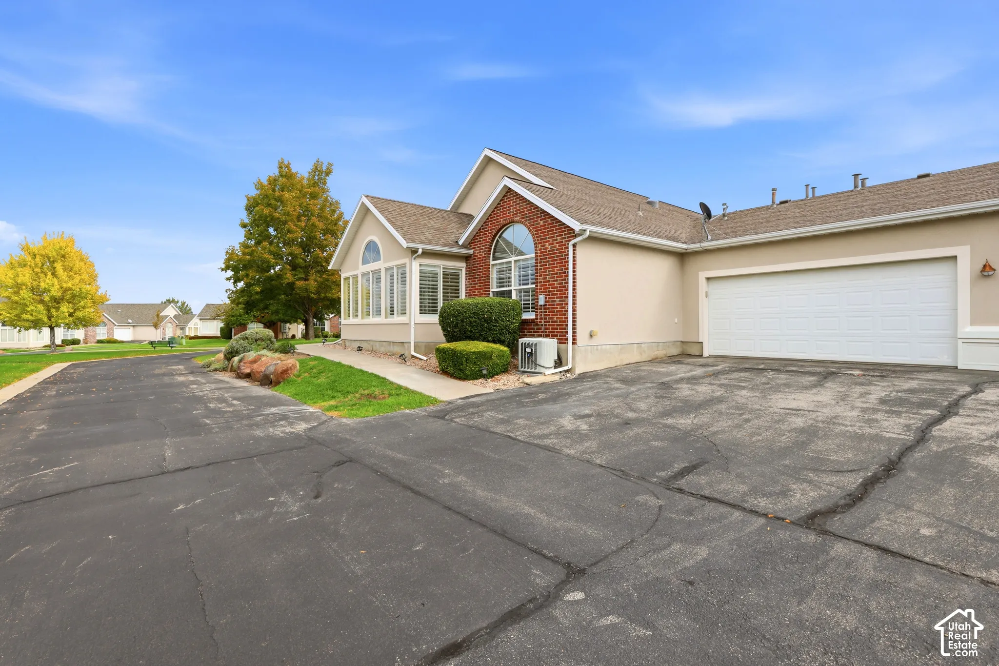 Exterior featuring a brick and newly re done stucco facade, arched windows, asphalt driveway, and attached garage
