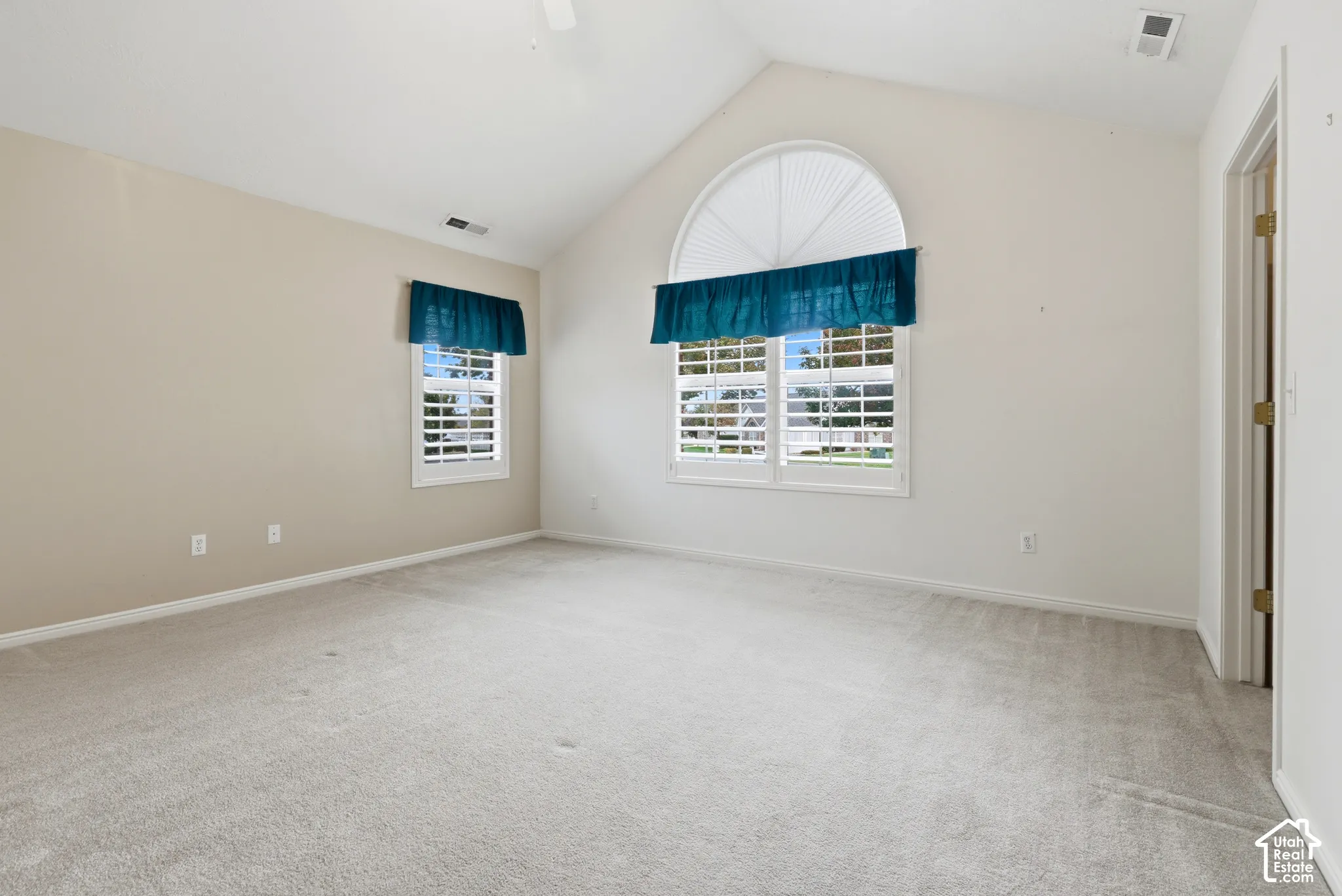 Main bedroom with arched window, wall-to-wall carpeting, and plantation-style shutters