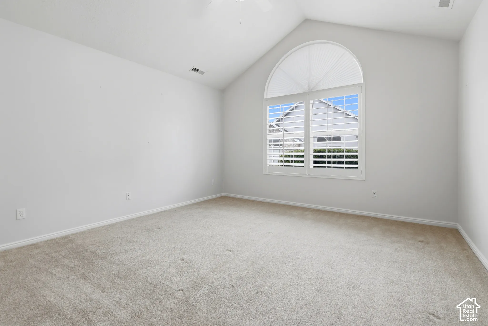 Guest bedroom with vaulted ceilings, arch-top window, and plantation shutters