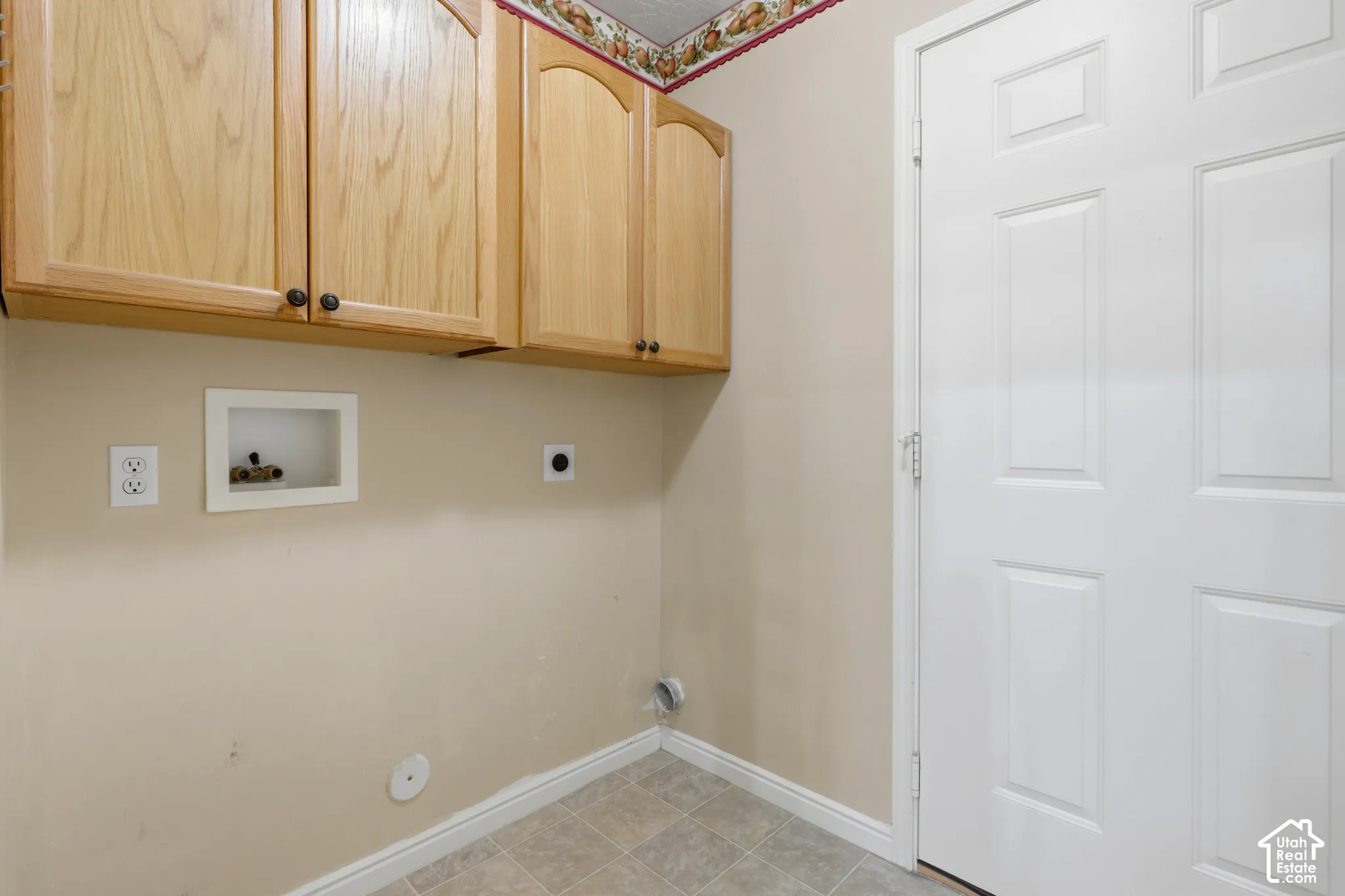 Utility space featuring wall-mounted wood cabinetry, patterned tile flooring, and a six-panel door