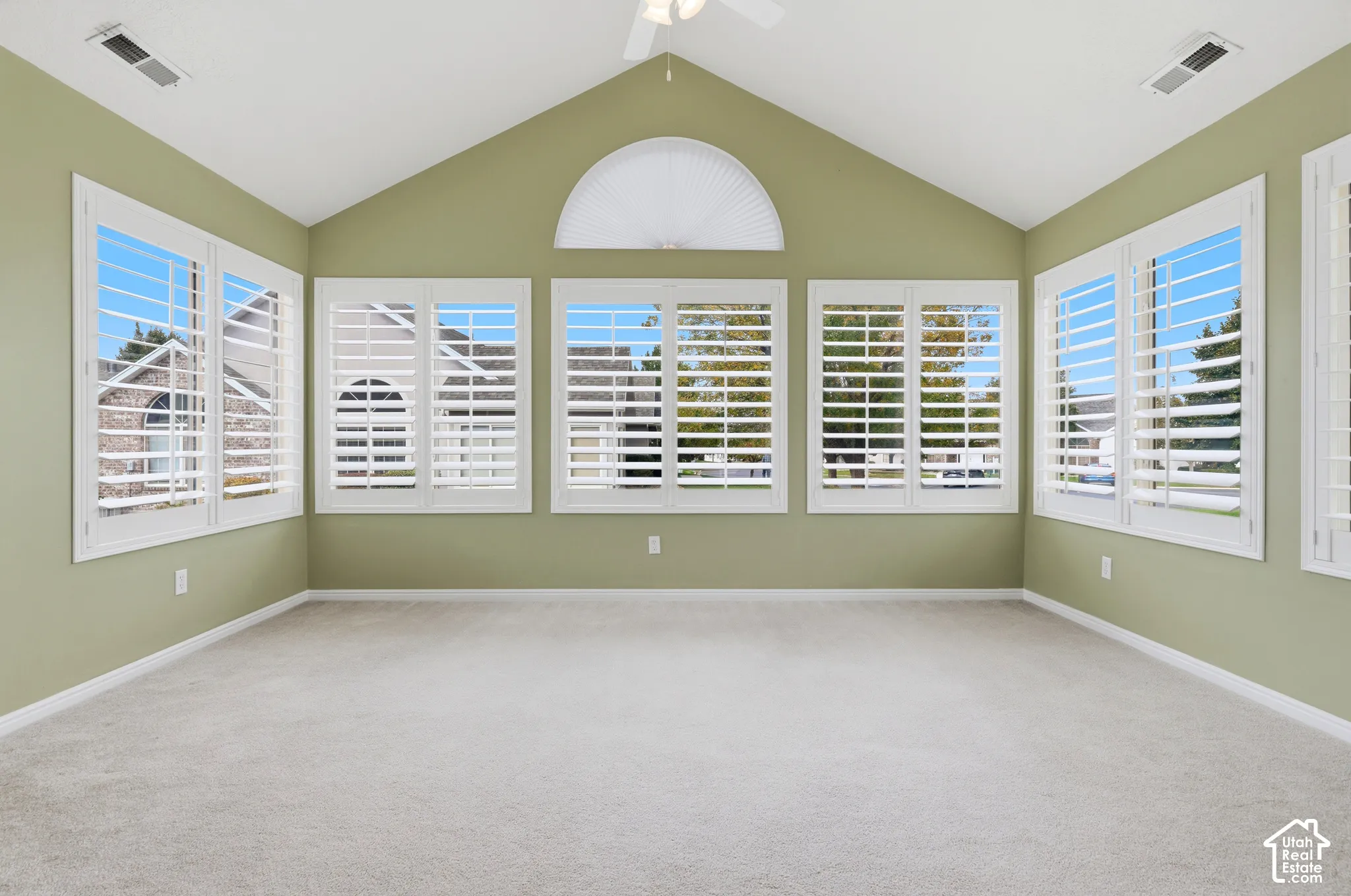 Sunroom/office space with vaulted ceilings featuring a central semi-circular window and multiple windows equipped with white plantation shutters