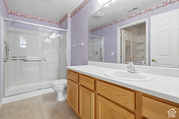 Main bathroom in main bedroom featuring a wood vanity with a white countertop, an integrated oval sink, a glass-enclosed shower with tiled surround, and a large wall-mounted mirror
