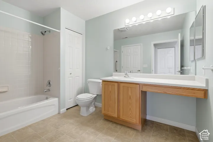 Bathroom in guest bedroom featuring a vanity with wood-finish cabinetry, an expansive countertop, a wall-to-wall mirror, and a tub-shower combination with tile surround