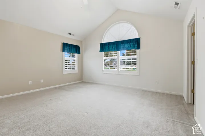Main bedroom with arched window, wall-to-wall carpeting, and plantation-style shutters