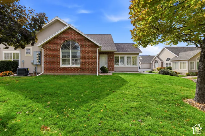 Exterior featuring a red brick facade, an arched window, a gabled roofline, and a manicured lawn
