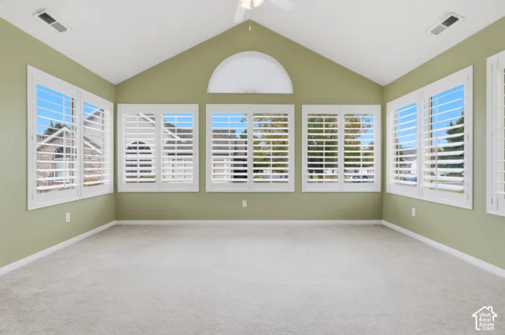 Sunroom/office space with vaulted ceilings featuring a central semi-circular window and multiple windows equipped with white plantation shutters