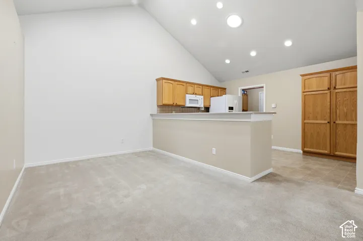 Vaulted ceiling featuring recessed lighting, sky lights and kitchen with wood cabinetry and built-in pantry, and a breakfast bar