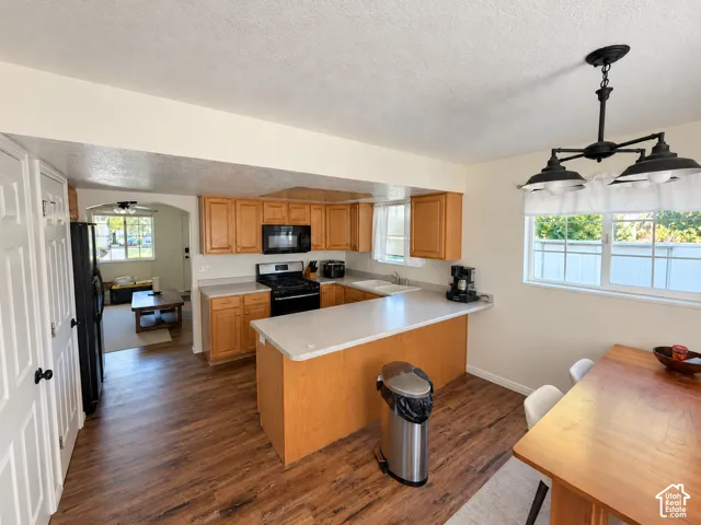 Kitchen featuring wood-finish flooring, wood cabinetry, a peninsula countertop, and an overhead multi-light fixture