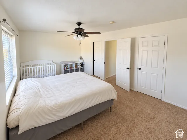 Neutral-toned carpeting, ceiling fan with integrated lighting, and six-panel interior doors