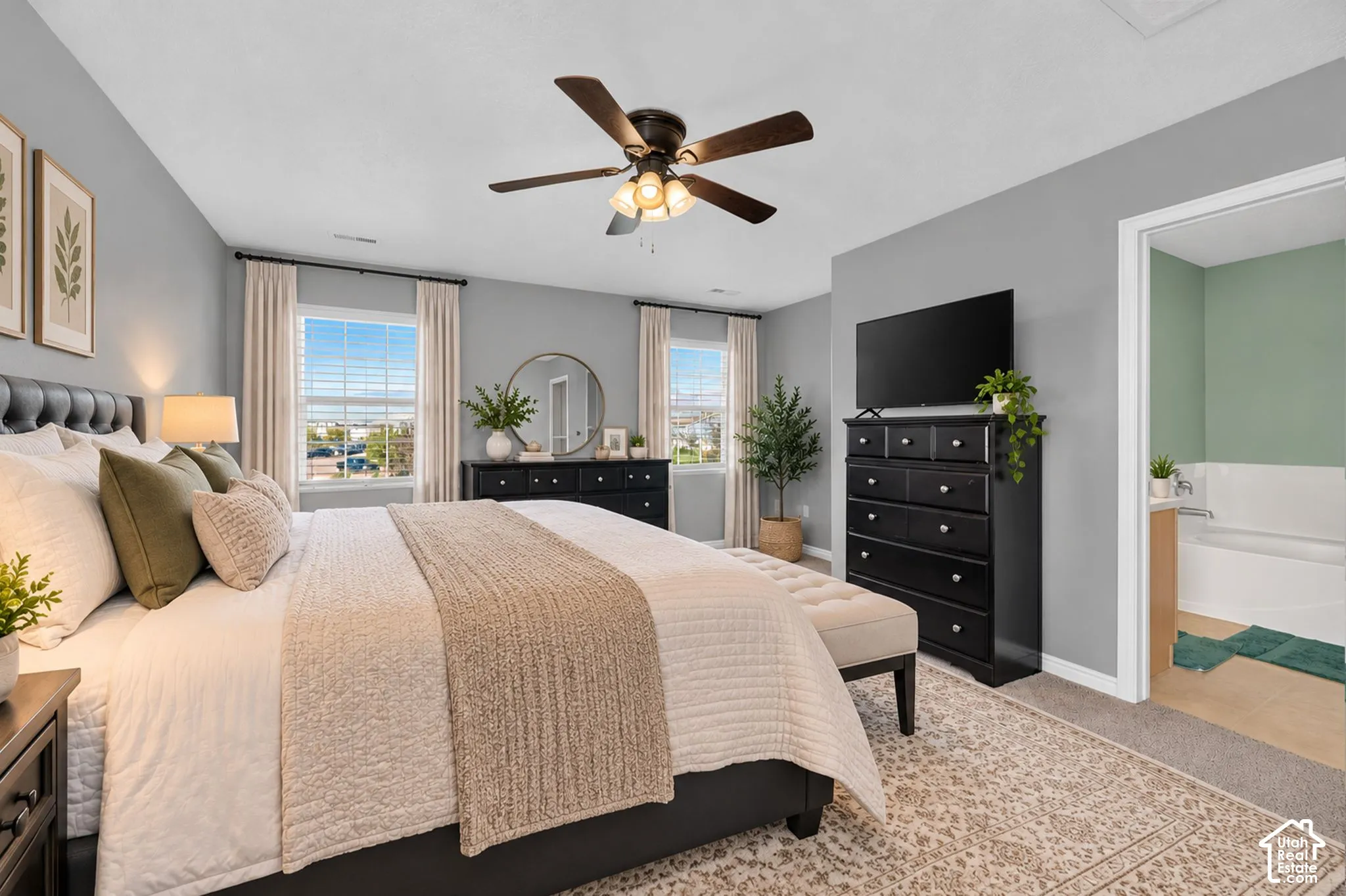 Neutral-toned bedroom featuring double-pane windows, carpeted flooring, and a ceiling fan with integrated lighting