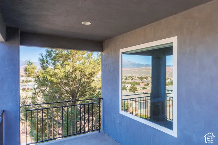 Covered balcony featuring smooth stucco walls, recessed lighting, and metal railing