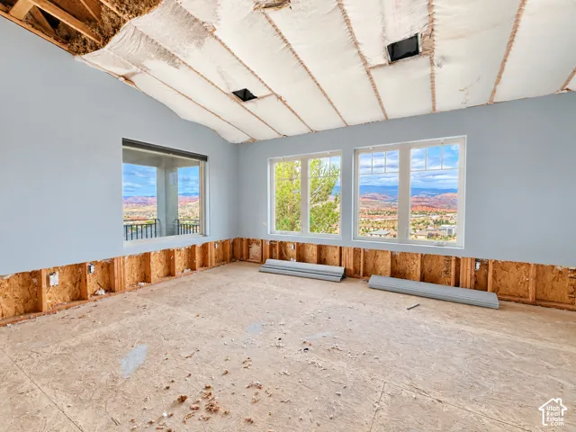 Interior space featuring vaulted ceilings, expansive multi-pane windows, and exposed wood-frame wall studs with panoramic mountain scenery