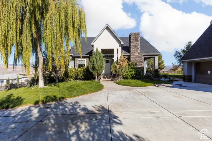 Exterior facade featuring stone veneer masonry, covered entryway, concrete driveway, and gabled roofline