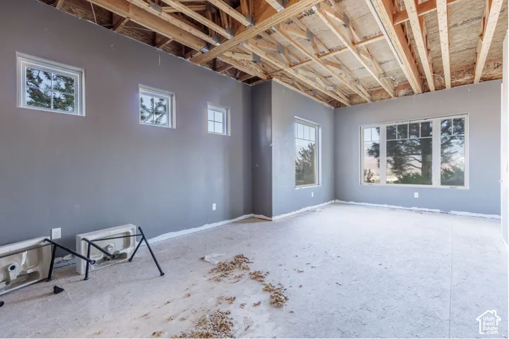 Open-concept room featuring exposed wooden roof trusses, multi-pane windows, and neutral-toned wall finish