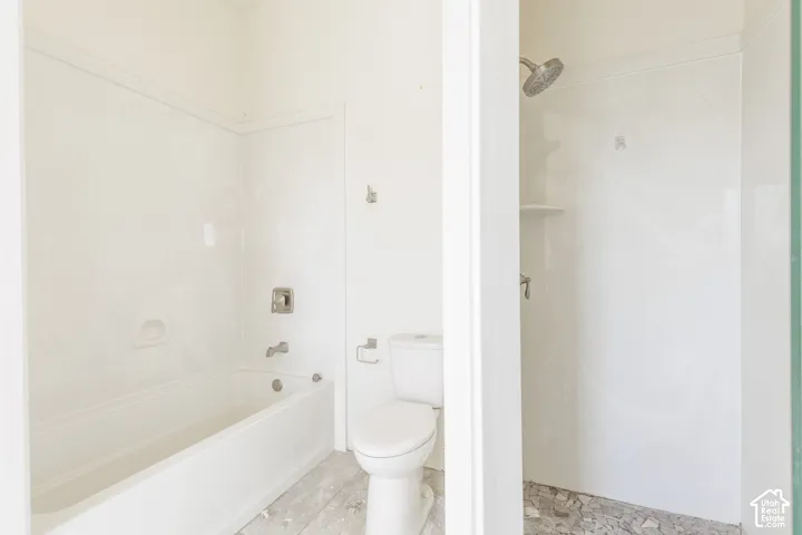 Bathroom featuring a soaking tub, separate shower stall with built-in shelving, white wall-surround panels, and a standard toilet