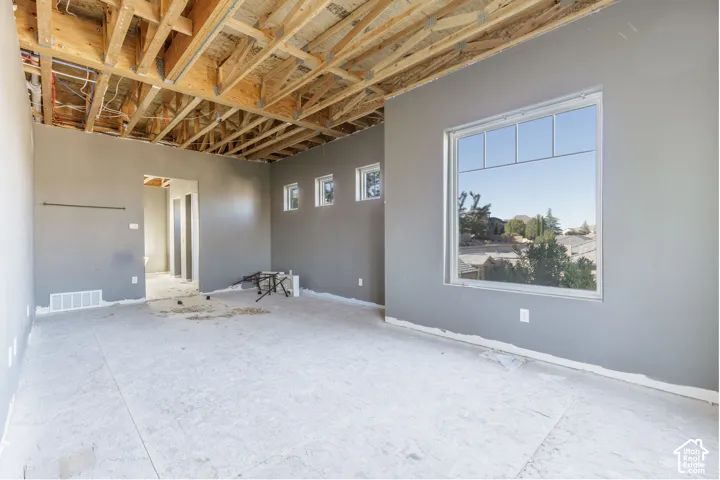 Interior space featuring an exposed wood truss ceiling, smooth grey-painted walls, and a large fixed-pane window with additional triple clerestory windows