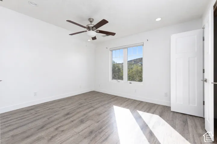 Room featuring wood-finish flooring, recessed lighting, a brushed-nickel ceiling fan with integrated light fixture, and a window with exterior mountain scenery