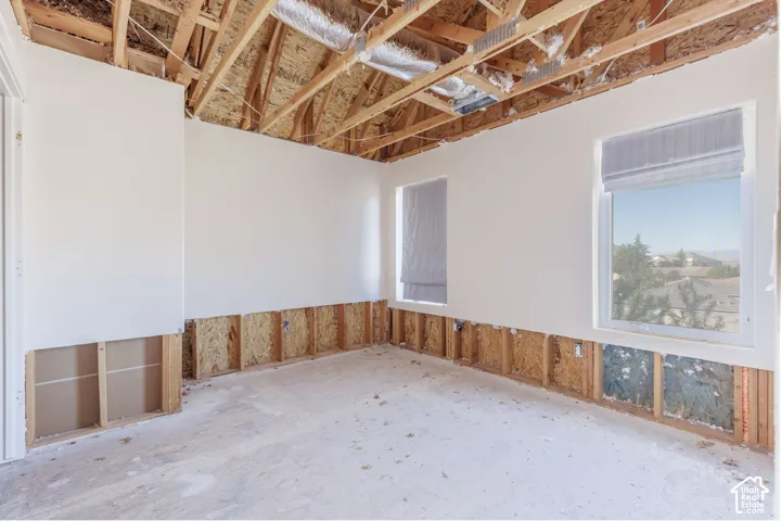 Interior space featuring exposed wood framing, vaulted ceiling, and dual windows