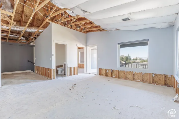 Open-concept interior space featuring exposed wood roof trusses, vaulted ceilings, and a large picture window