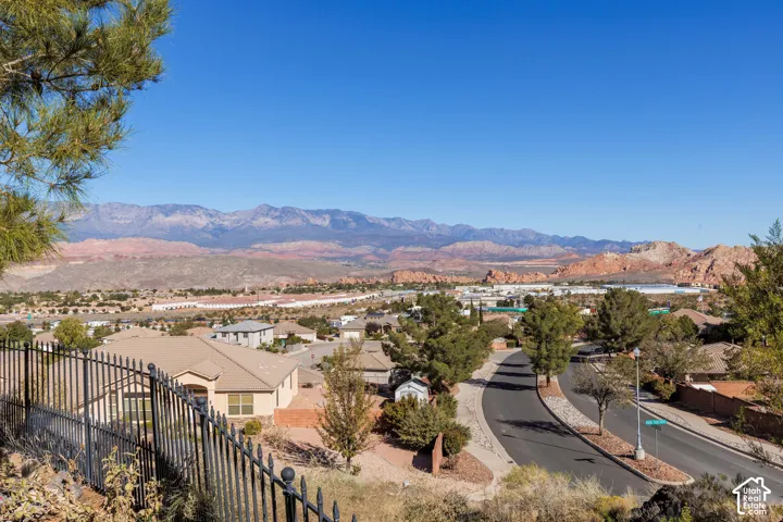 Panoramic mountain backdrop and arid landscape scenery featuring a black metal perimeter fence