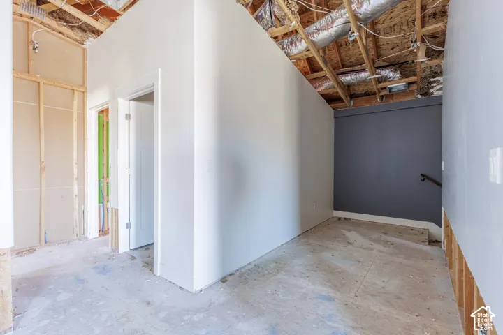 Interior space featuring exposed wood framing, an open-concept ceiling with visible mechanical ductwork, dual doorway entries, and a dark-toned accent wall