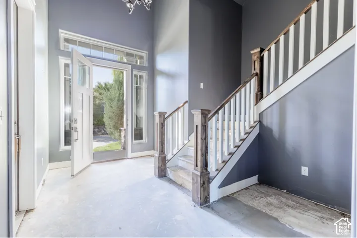 Foyer featuring a high ceiling, transom windows, a multi-pane glass entry door, and a staircase with a white balustrade and wood-finish posts