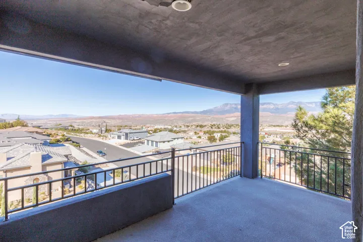 Covered balcony featuring concrete flooring, recessed ceiling lighting, and black metal railings overlooking a mountain range