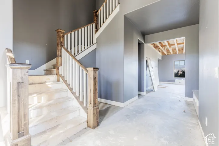 Staircase featuring wood-finish newel posts and white balusters, high ceilings, and neutral-toned wall paint