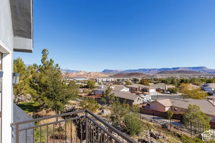 Elevated balcony with a dark metal railing and mountain scenery