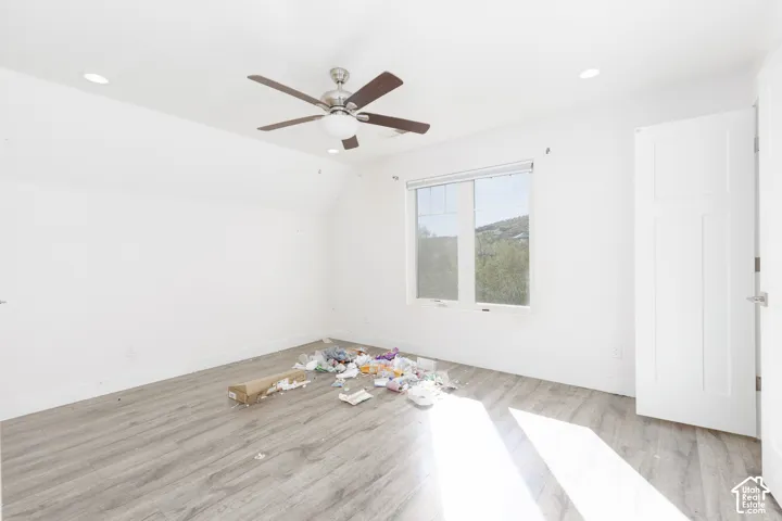 Interior space featuring wood-finish flooring, recessed lighting, a ceiling fan with integrated light fixture, a window with exterior landscape, and a multi-panel door