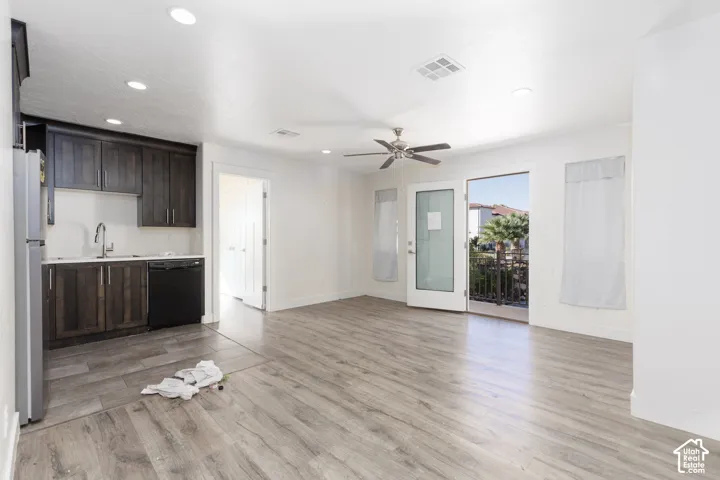 Kitchenette featuring dark-finish cabinetry, a black dishwasher, a stainless steel faucet, recessed lighting, and wood-finish flooring