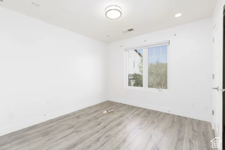 Room featuring wood-finish flooring, recessed lighting, a ceiling-mounted light fixture, and a multi-pane window