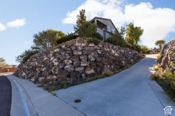 Multi-level exterior featuring natural stone retaining walls, concrete driveway, and elevated landscaping