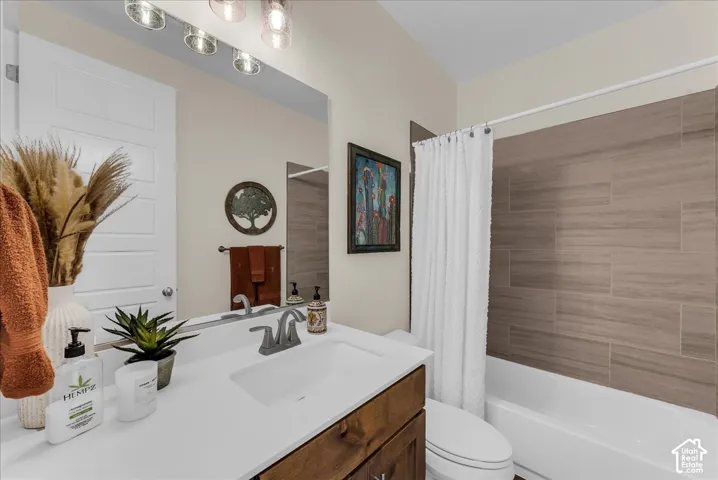 Bathroom featuring a wood-finish vanity with a white countertop, an integrated rectangular sink, a wall-to-wall mirror, and a bathtub with horizontal tile surround