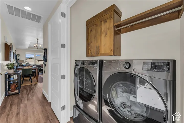 Laundry area featuring wood-finish cabinetry, a built-in hanging rod, and stainless-finish appliances