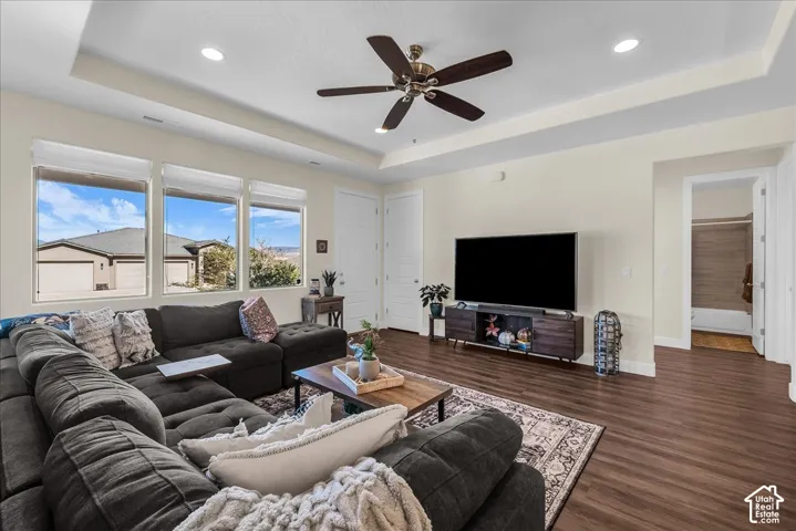 Tray ceiling with recessed lighting, central ceiling fan, and wood-finish flooring