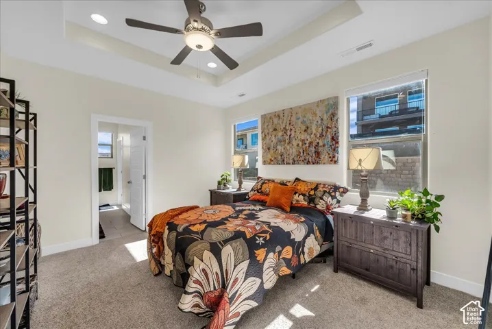 Tray ceiling with recessed lighting and a central ceiling fan, neutral wall tones, and large windows