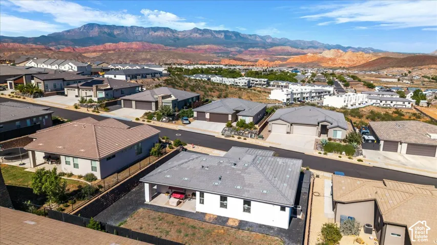 Aerial perspective featuring a single-story residence with a concrete tile roof, a covered rear patio, and a mountain range backdrop