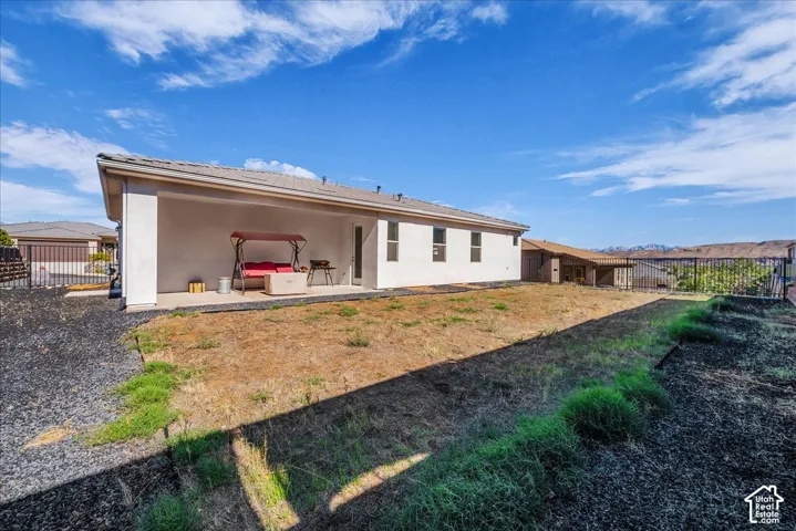 Backyard featuring a covered concrete patio, perimeter metal fencing, and mountain backdrop