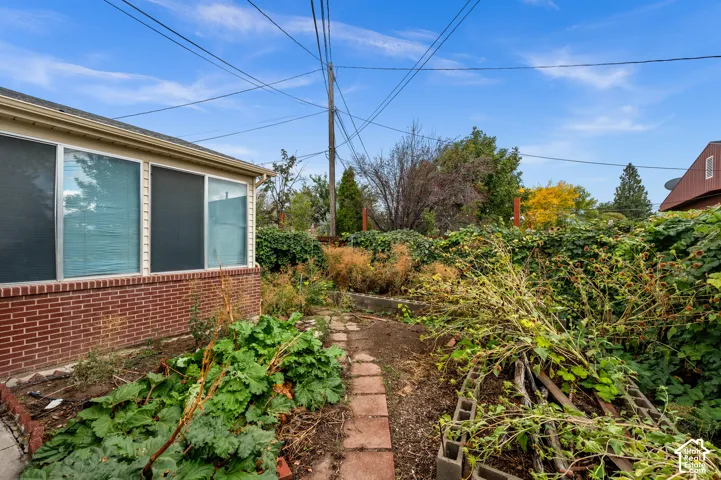 Exterior of brick construction featuring a concrete masonry unit retaining wall, a paved walkway, and established landscaping