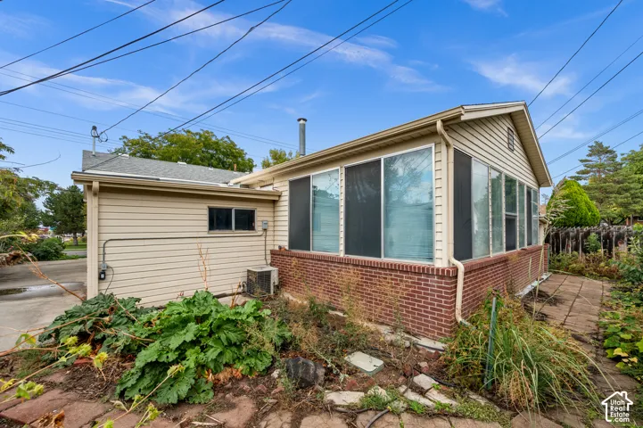 Exterior featuring horizontal siding, a red brick base, large windows, and a paved stone patio