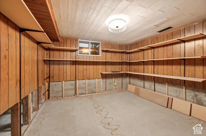 Wood paneling with extensive built-in shelving, concrete flooring, and a flush-mount drum ceiling light