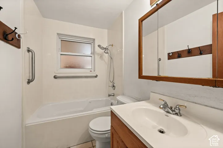 Bathroom featuring a wood-finish vanity with a molded countertop and integrated sink, a deep soaking tub with shower combination, and a large wood-framed medicine cabinet