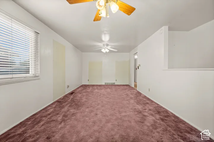 Interior space featuring wall-to-wall carpeting, dual ceiling fans with integrated lighting, and horizontal window blinds