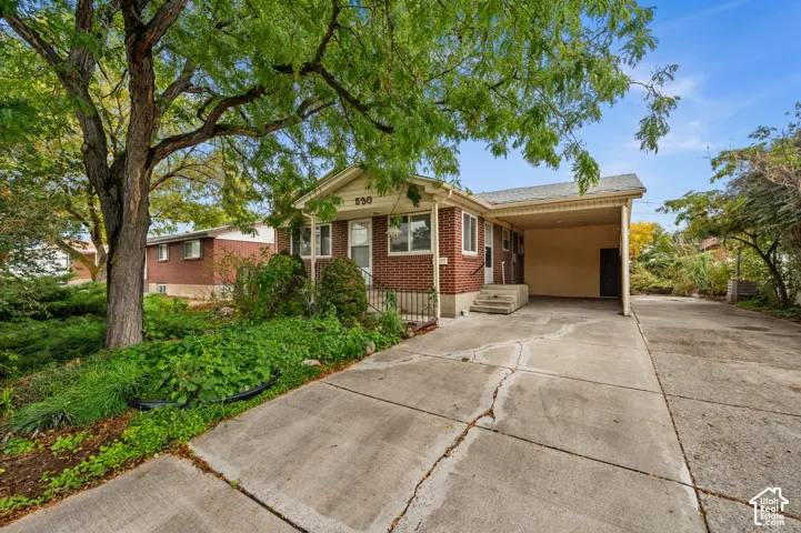 Brick exterior, concrete driveway, attached carport, and mature trees