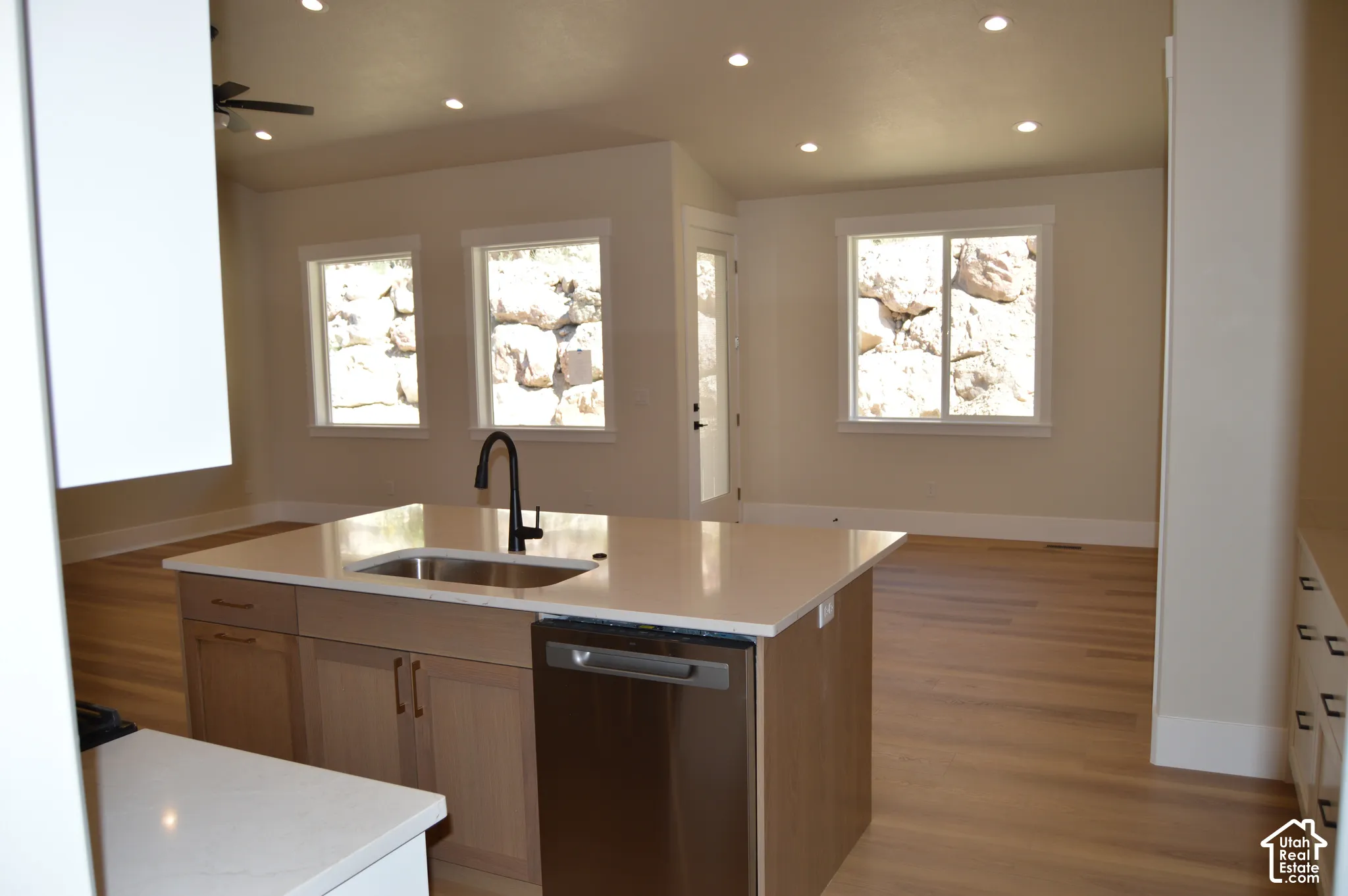 Kitchen featuring a center island with a quartz countertop, undermount sink, matte black faucet, wood-finish cabinetry, and recessed lighting