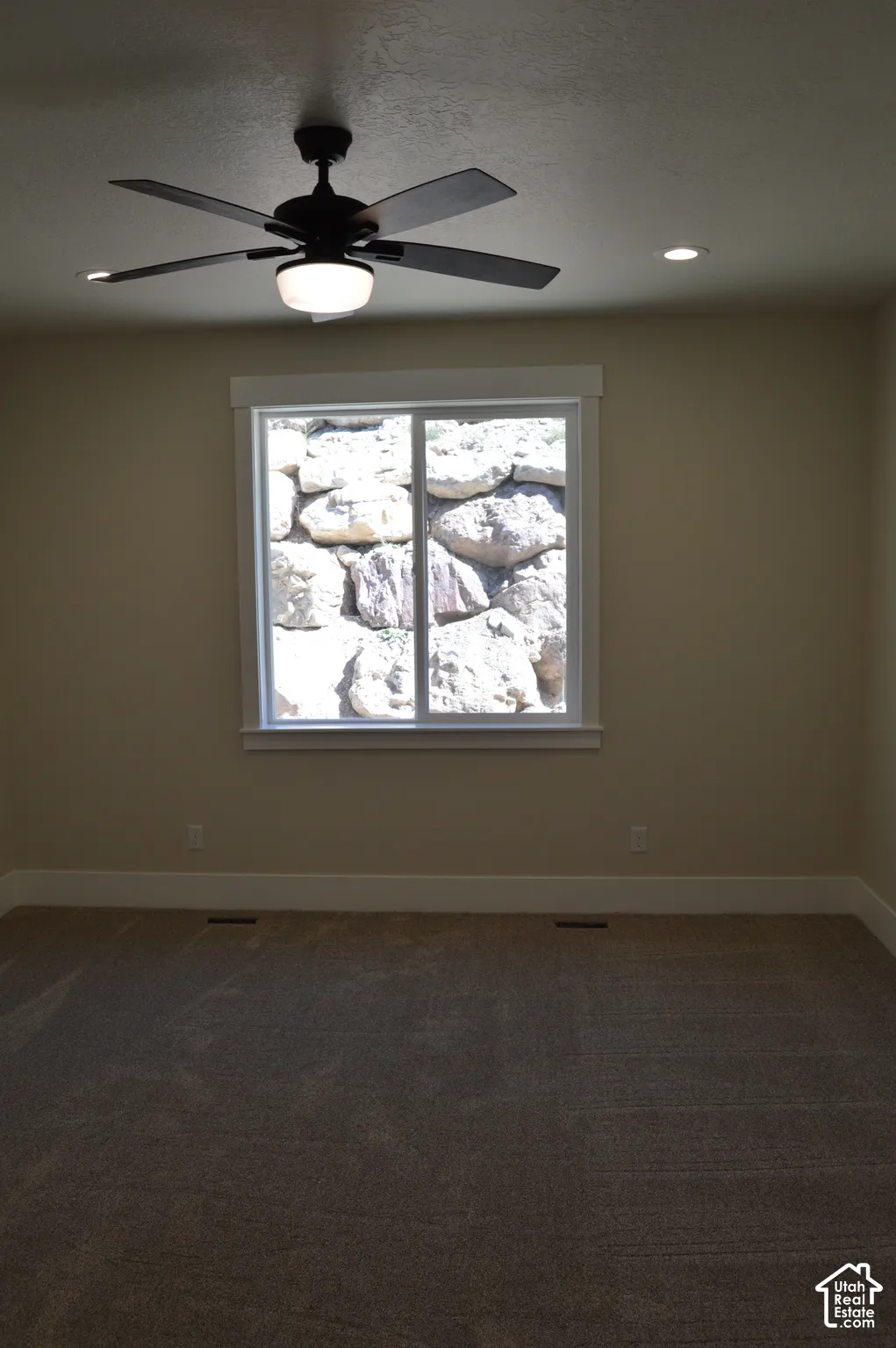 Room featuring a ceiling fan with integrated light, recessed lighting, neutral carpeting, and a sliding window with a stone landscape backdrop