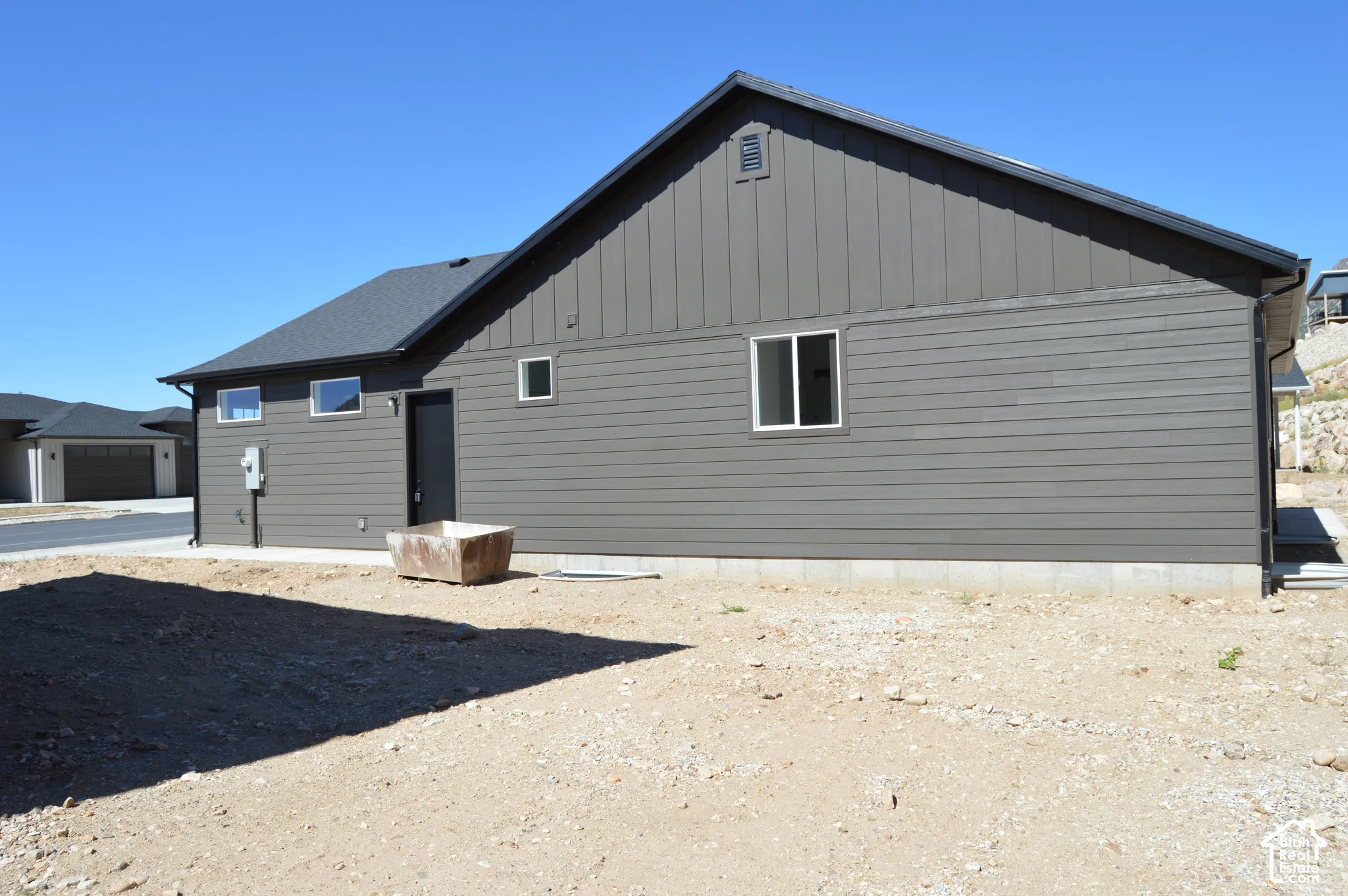 Exterior features include dark horizontal and vertical siding, a gabled roofline, and rectangular white-framed windows