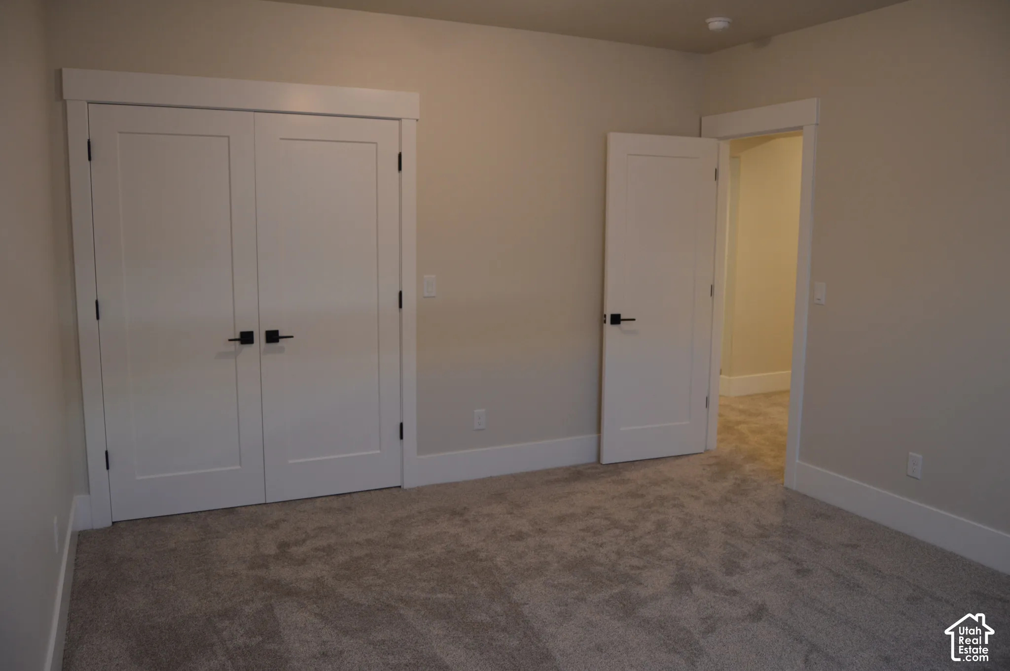 Neutral wall tones with carpeted flooring, white shaker-style interior doors, and matte black hardware