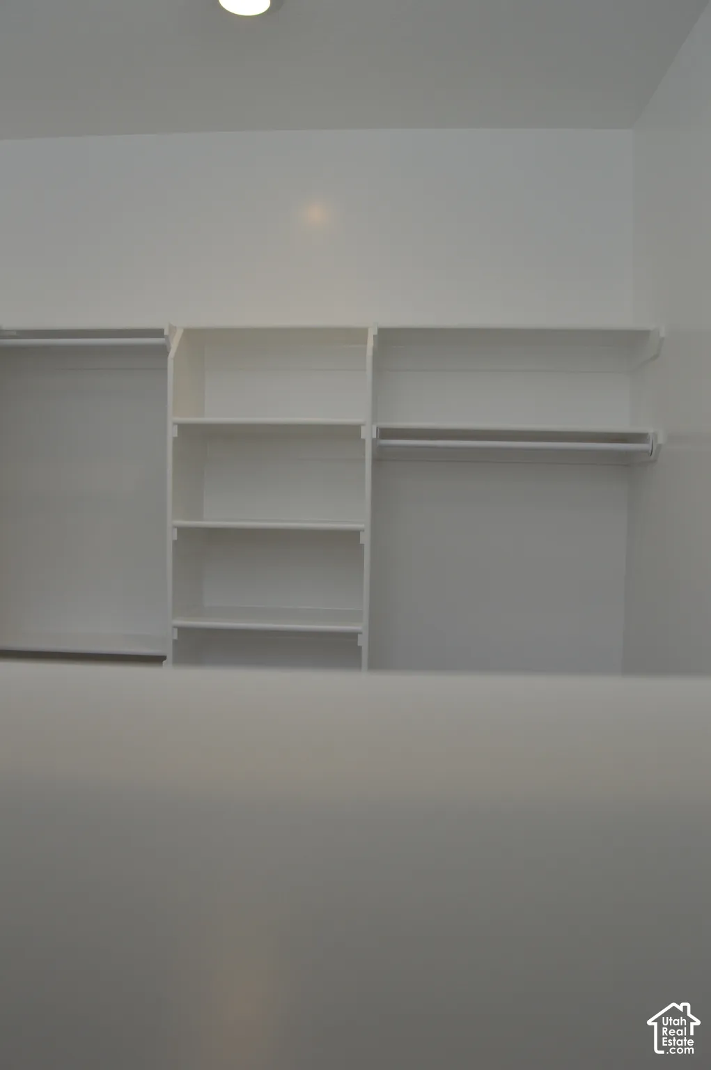 Custom white built-in shelving featuring integrated hanging rods and multiple storage compartments